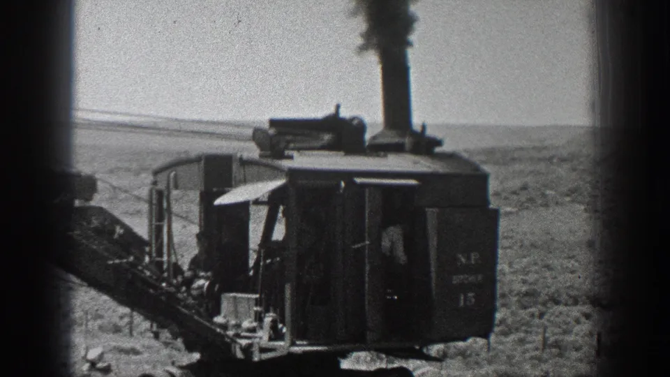 The 1936 California desert scene shows the steam-powered machine closer to camera, with dark smoke rising and an operator partly visible.