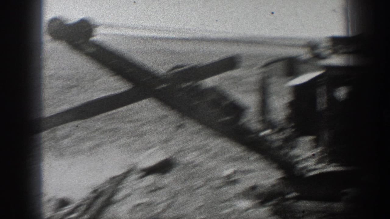 1936 California home-movie frame showing a steam excavator boom over dirt, with the machine partly obscured by dark film-edge shadows.