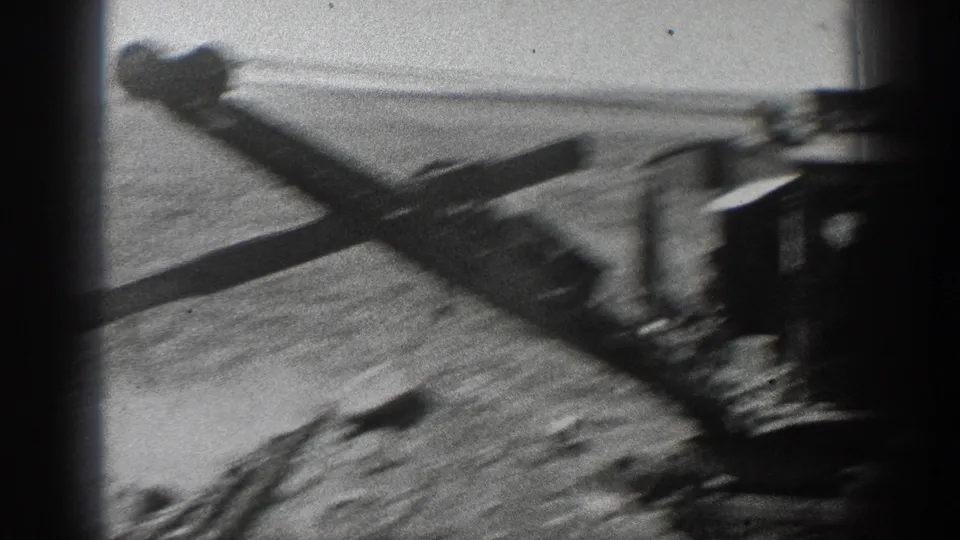 1936 California home-movie frame showing a steam excavator boom over dirt, with the machine partly obscured by dark film-edge shadows.