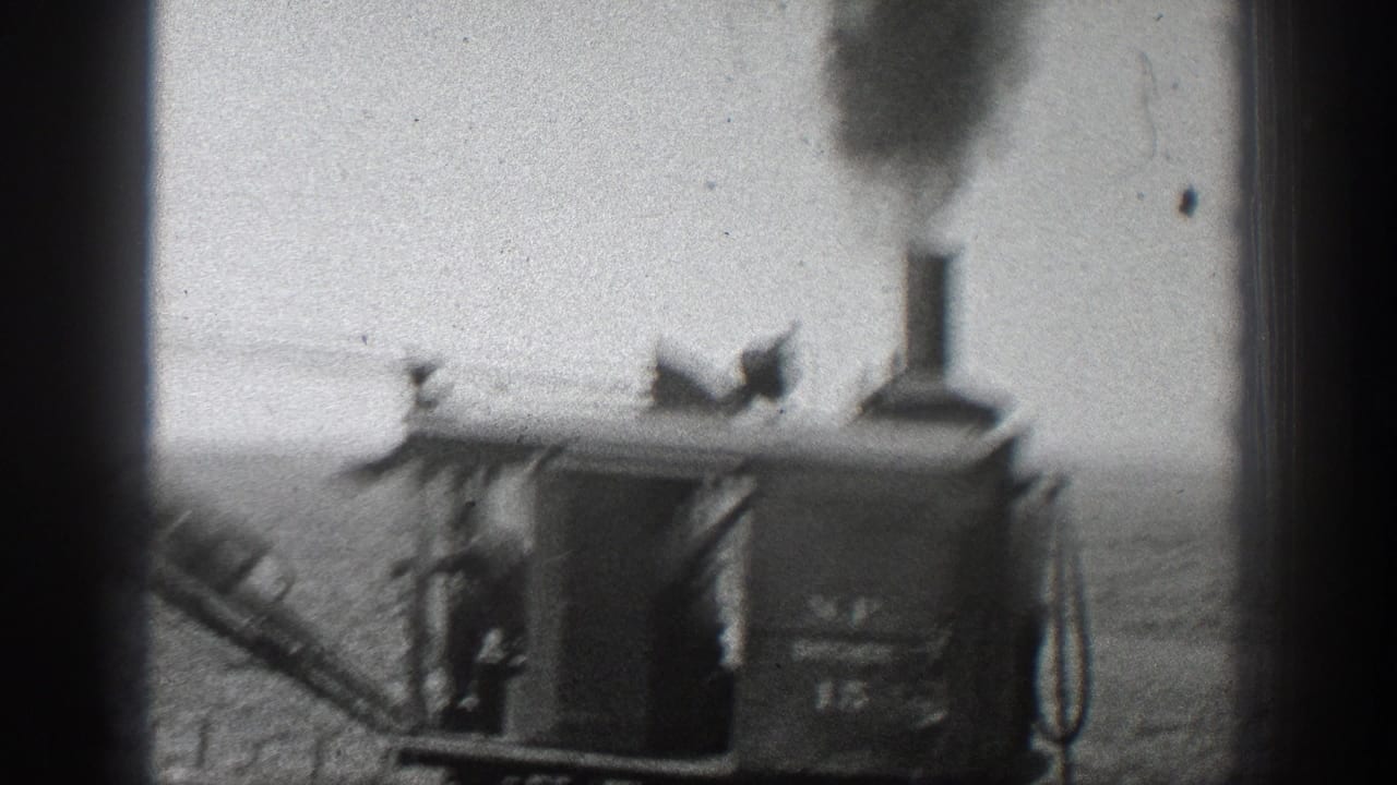 Steam excavator cab with smoke stack and boom visible against a barren hillside.