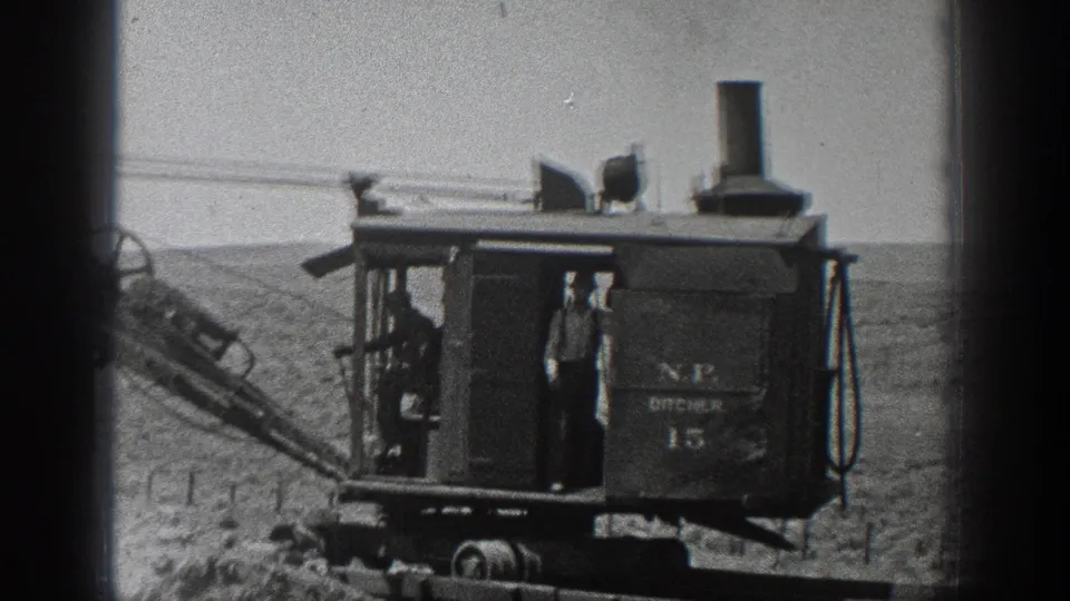 1936 California home-movie frame showing workers around a rail-mounted steam excavator with visible lettering and the number 15.