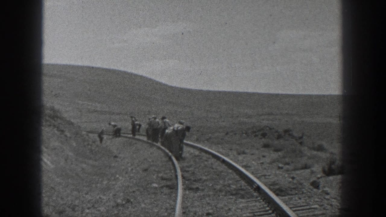 1936 California home-movie frame showing men in hats walking beside a curved railroad track in a dry open landscape.