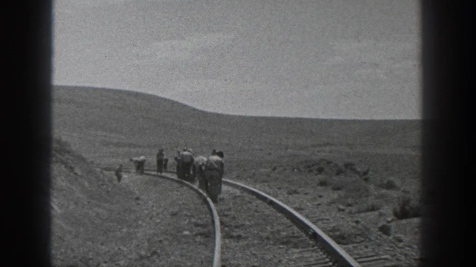 Men in work clothes appear on a curved rail line in 1936 California, filmed from a distance on black-and-white 8mm.
