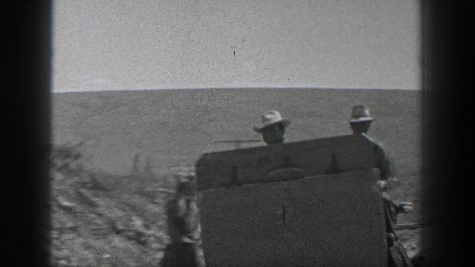 A closer 1936 California frame shows two hat-wearing men seated on a small railroad handcar against a barren hillside.
