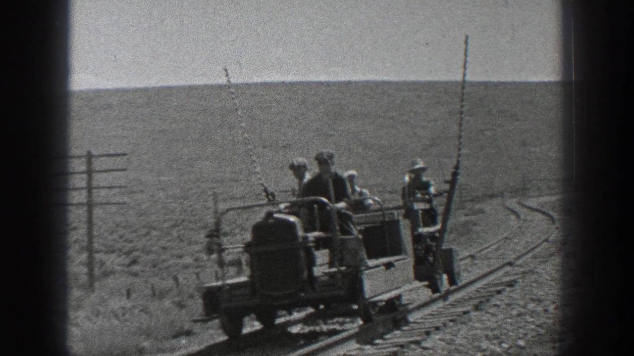 Men ride or stand near a small rail maintenance vehicle on curved track.