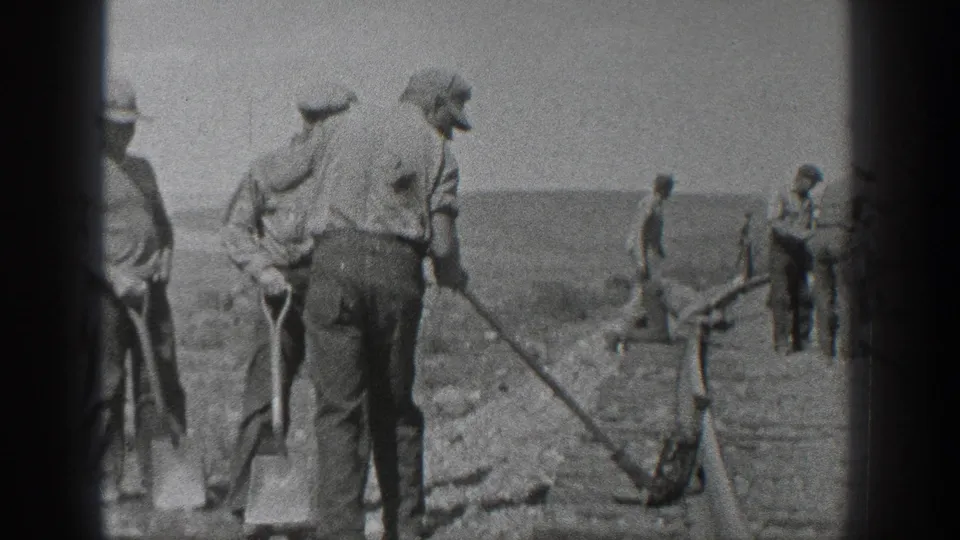 Men with shovels maintain railroad track in 1936 California, working beside rails in a flat, dry landscape.