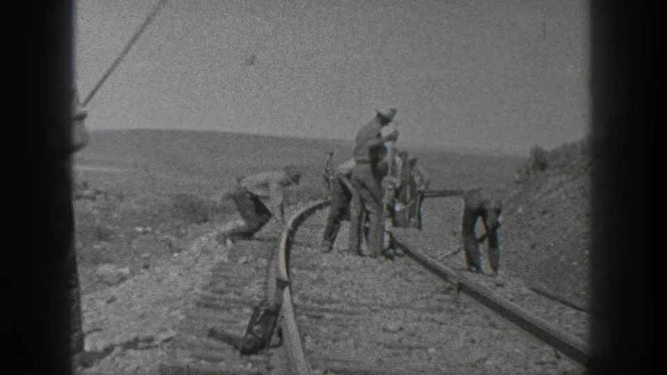 Black-and-white 8mm frame from the supplied 1936 California clip showing a crew gathered along railroad tracks during hand maintenance work.