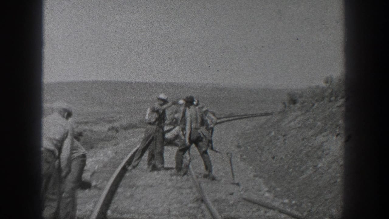California 1936 frame with several men standing and working beside rail lines near a sloped dirt embankment.