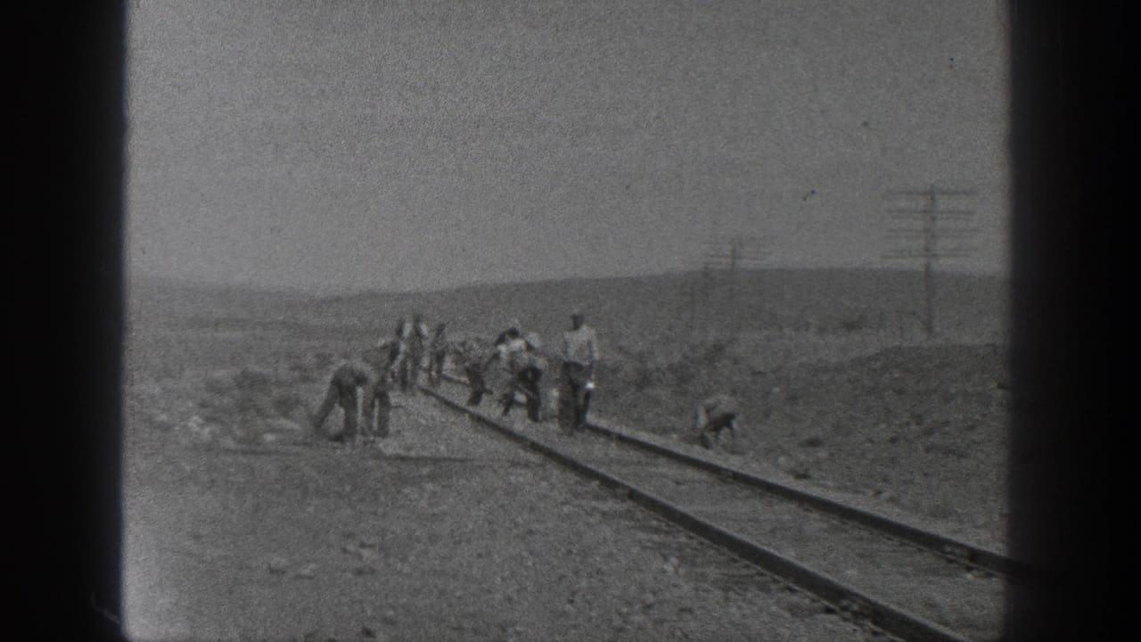A rural California railroad crew appears to work by hand on the rails, with poles and low hills behind them.