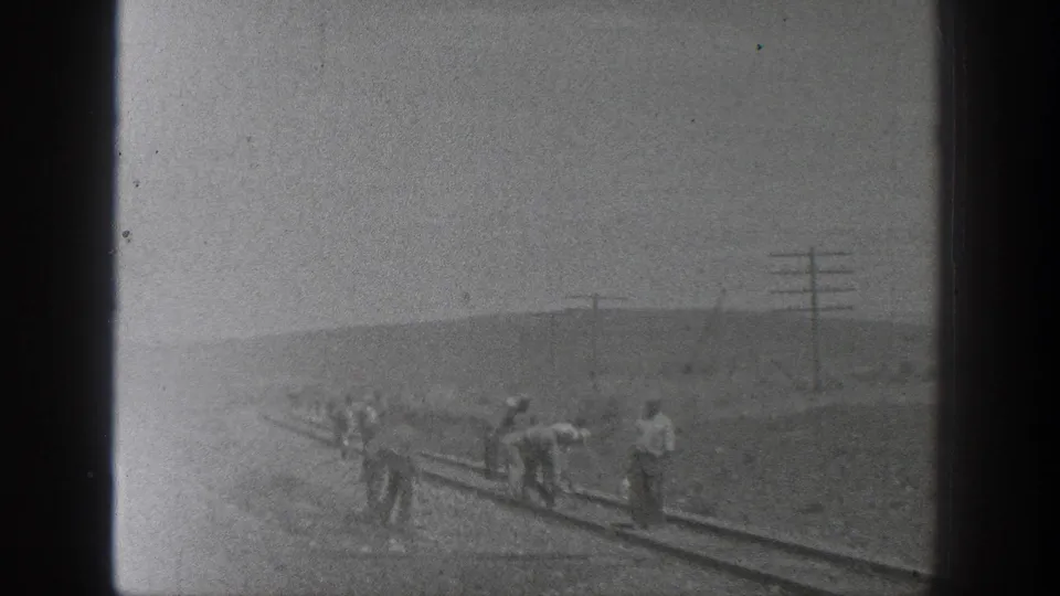 A softer 1936 California frame shows railroad workers dispersed along the rails, partly obscured by exposure and film haze.