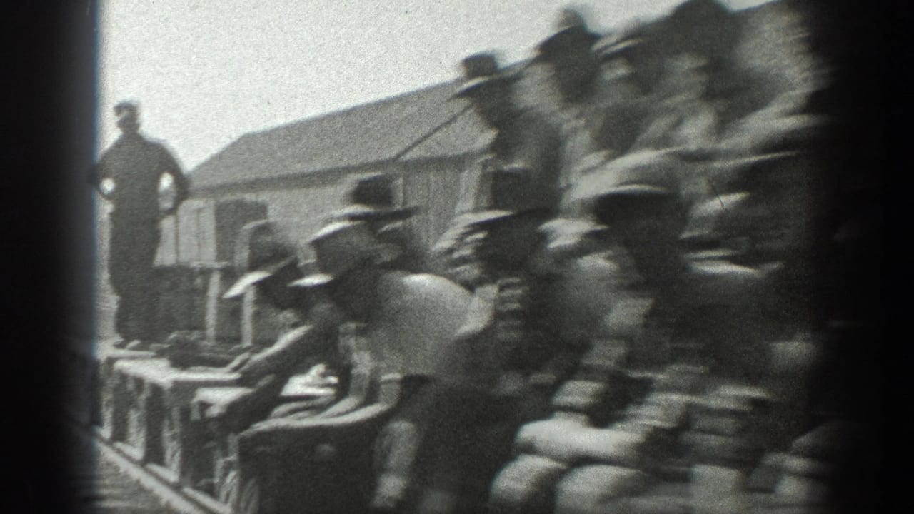 1936 California home-movie frame showing men in work clothes gathered by a railroad line near freight equipment.