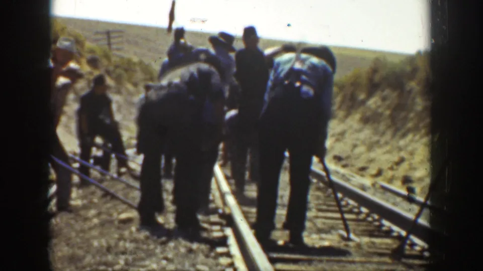 1936 California 8mm frame showing railway workers on a rural track, with tools, rails, wooden ties, and dry embankments visible.