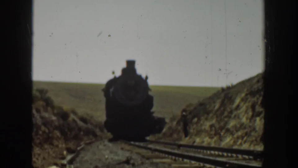 1936 California 8mm frame showing a closer head-on view of a steam locomotive on rural rails.