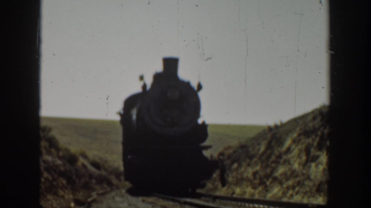 1936 California 8mm frame showing a steam locomotive approaching along a rural railway cut.