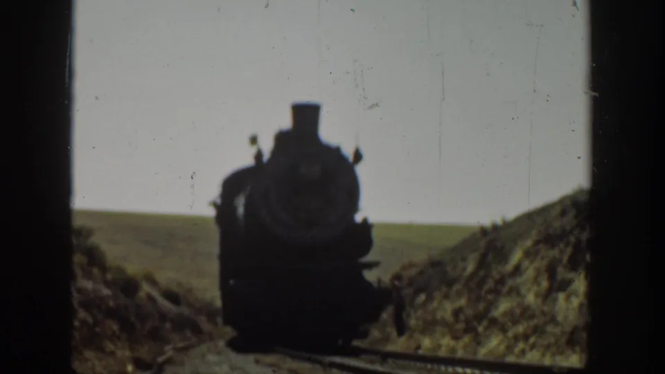1936 California 8mm frame showing a steam locomotive approaching along a rural railway cut.