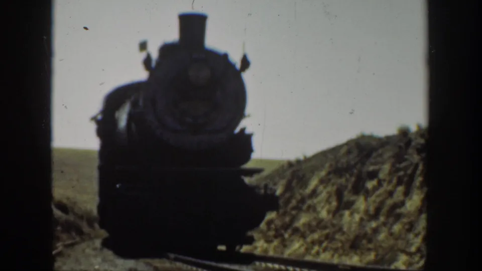 Steam locomotive nears the camera on a rural California railway, framed by dark 8mm film edges.