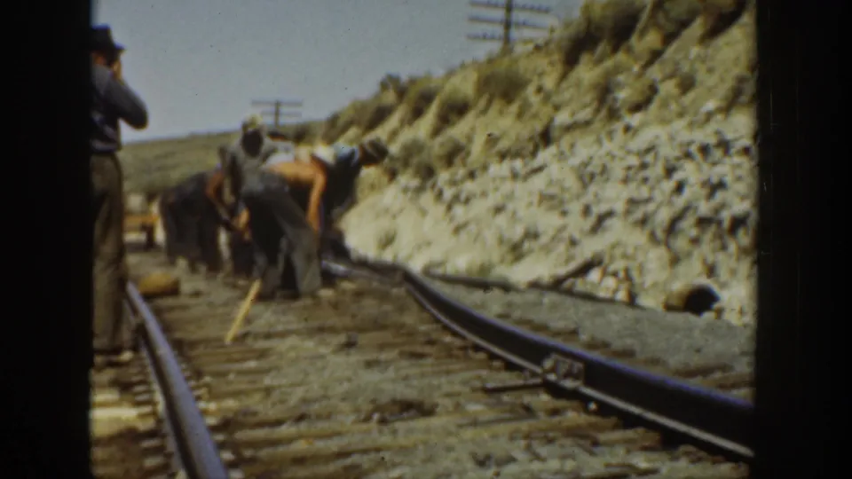 1936 California home-movie frame of railroad maintenance workers clustered along the rails in open dry terrain.