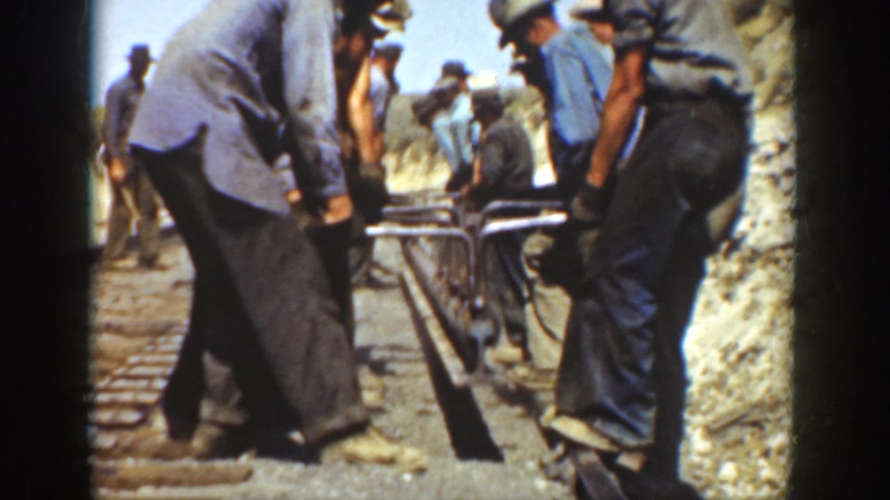 Adult men in work clothes appear to adjust a rail line by hand in 1936 California home-movie footage.