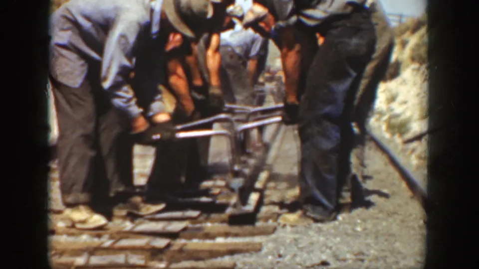 A rail crew appears to secure or adjust track by hand in sunlit 1936 California home-movie footage.