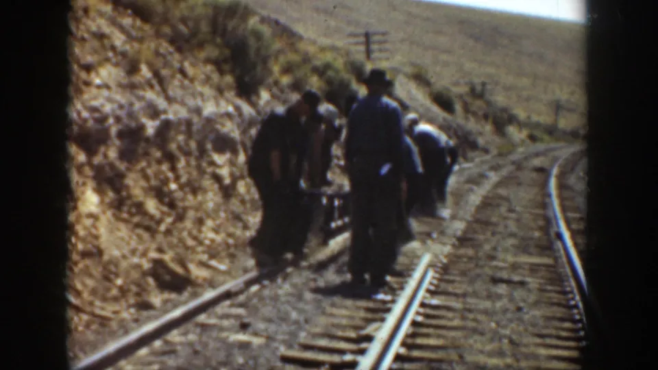 Railway workers repair track along a winding rail line in California, 1936, seen through an 8mm home-movie frame.