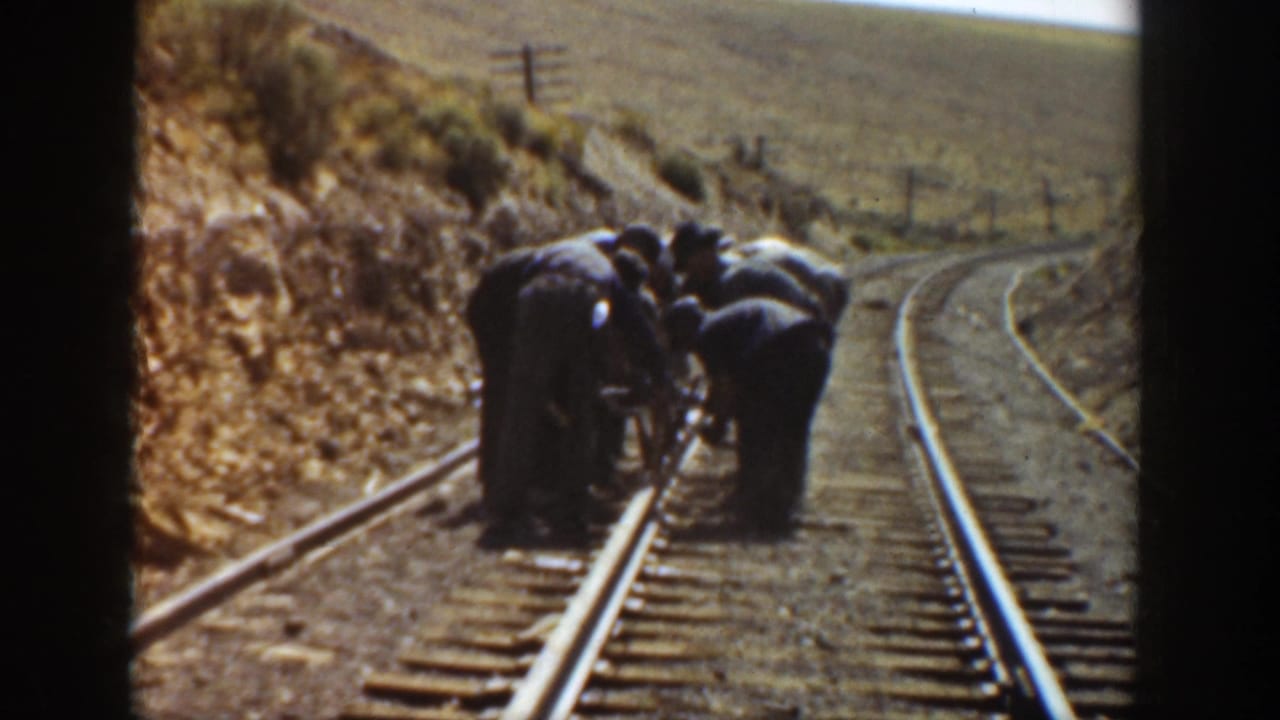 Railroad workers in dark clothing work together on a curving California track in the supplied 1936 footage.