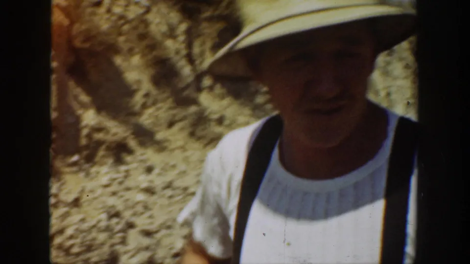 A railroad worker in a straw hat and suspenders stands near the track in 1936 California home-movie footage.