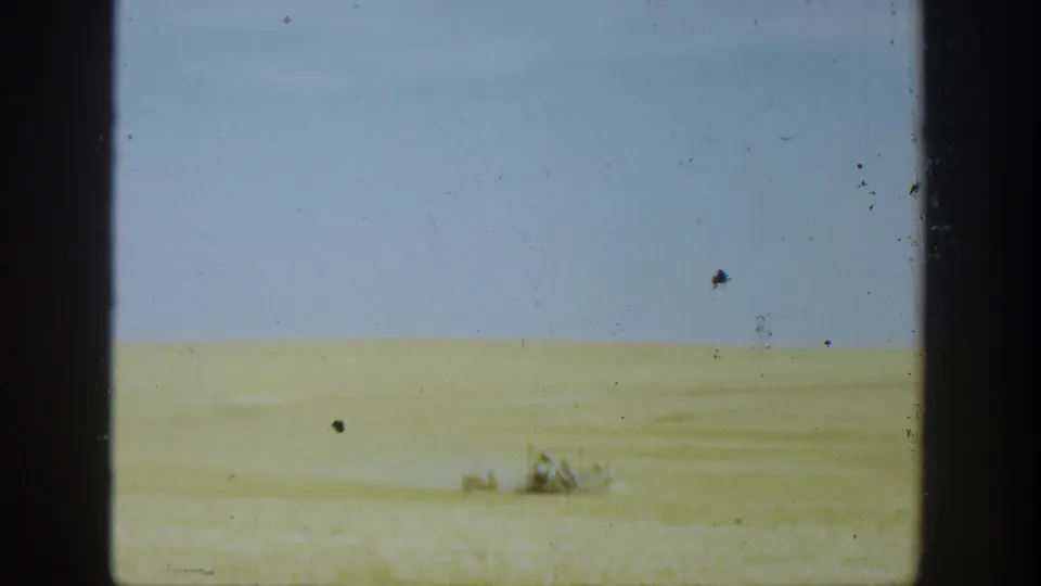 Wide 1936 California farm view with golden wheat and a distant reaper moving across the field.