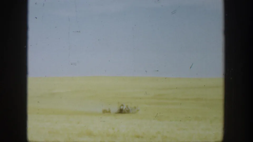 Expansive California wheat field in 1936, with distant harvesting machinery barely visible in the grain.
