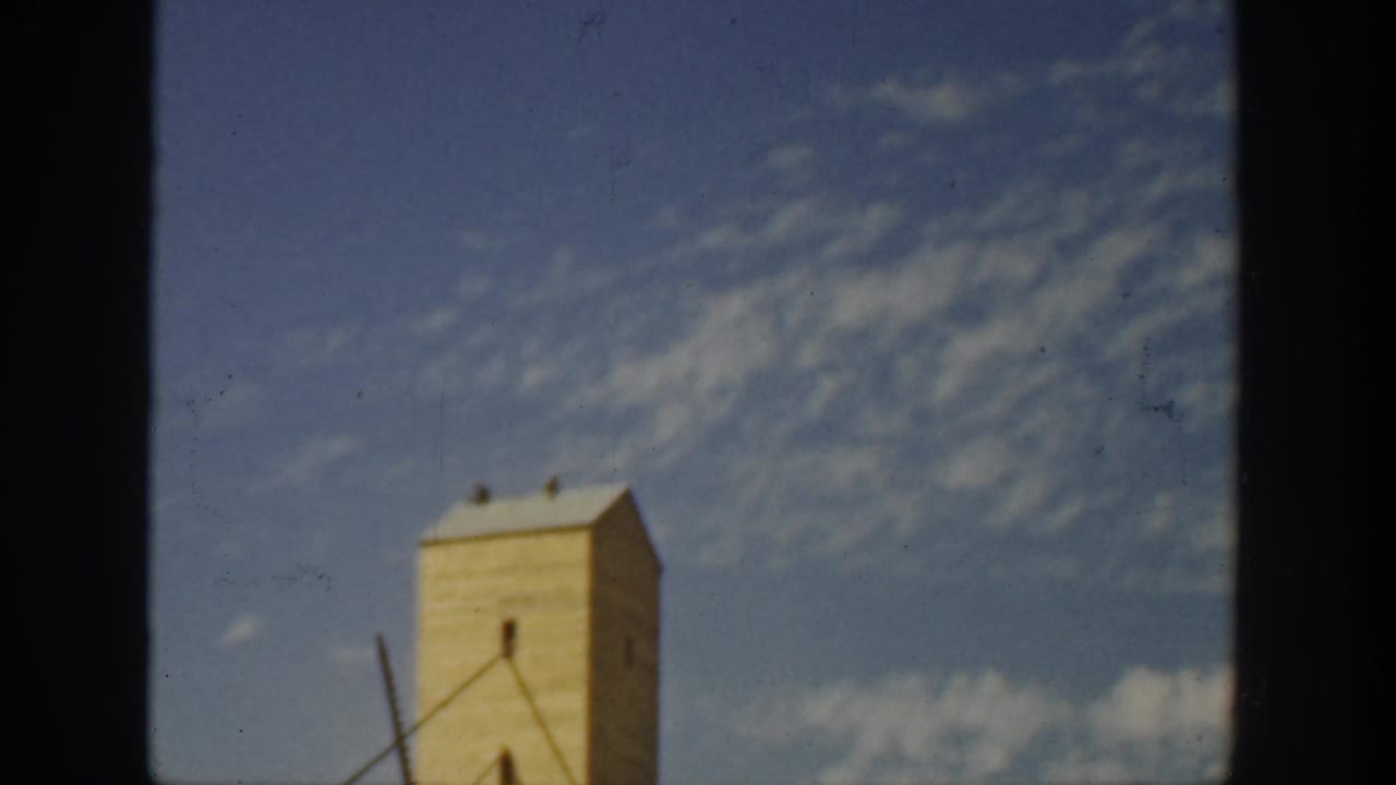Upper industrial tower framed beside dark film gate borders.