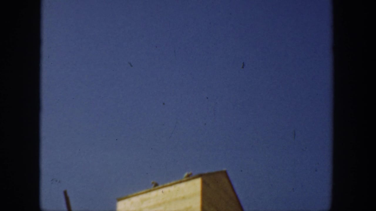 1936 California 8mm frame tilted upward to clear blue sky, with only the top edge of a yellow farm structure visible.