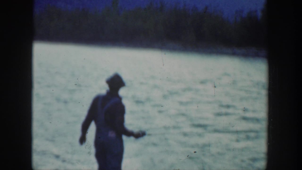 In 1936 California home-movie footage, a man in a hat and suspenders stands by a swift river with fishing gear.