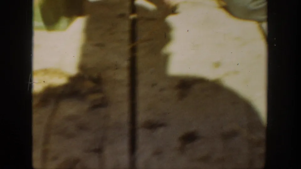 Soft 8mm frame from California in 1936 showing the frog close to a person's lower body, with heavy shadows and visible film grain.