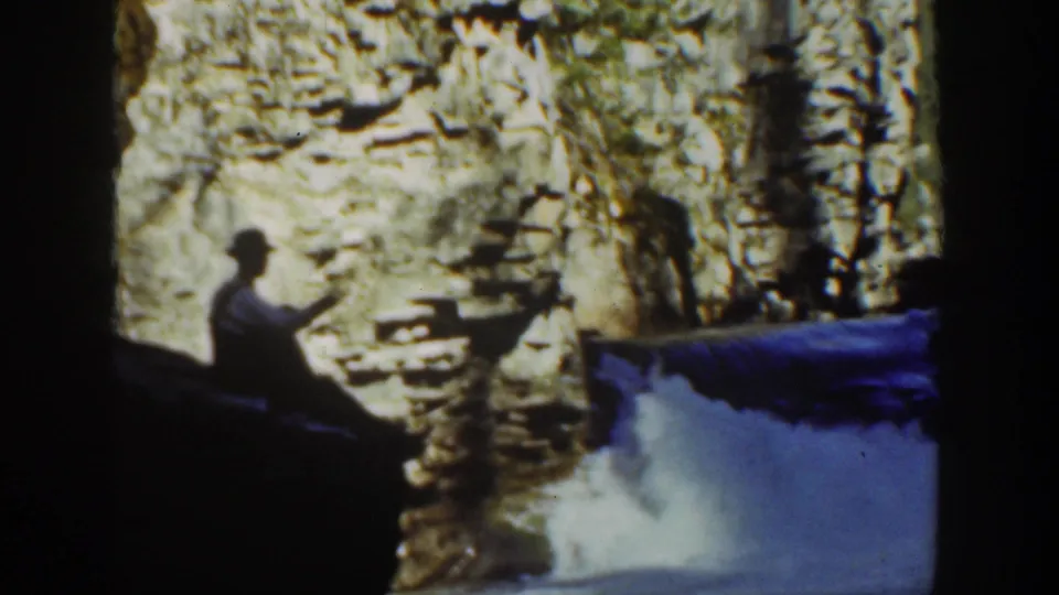 1936 California 8mm frame with a seated visitor near a canyon waterfall, one arm raised or extended.