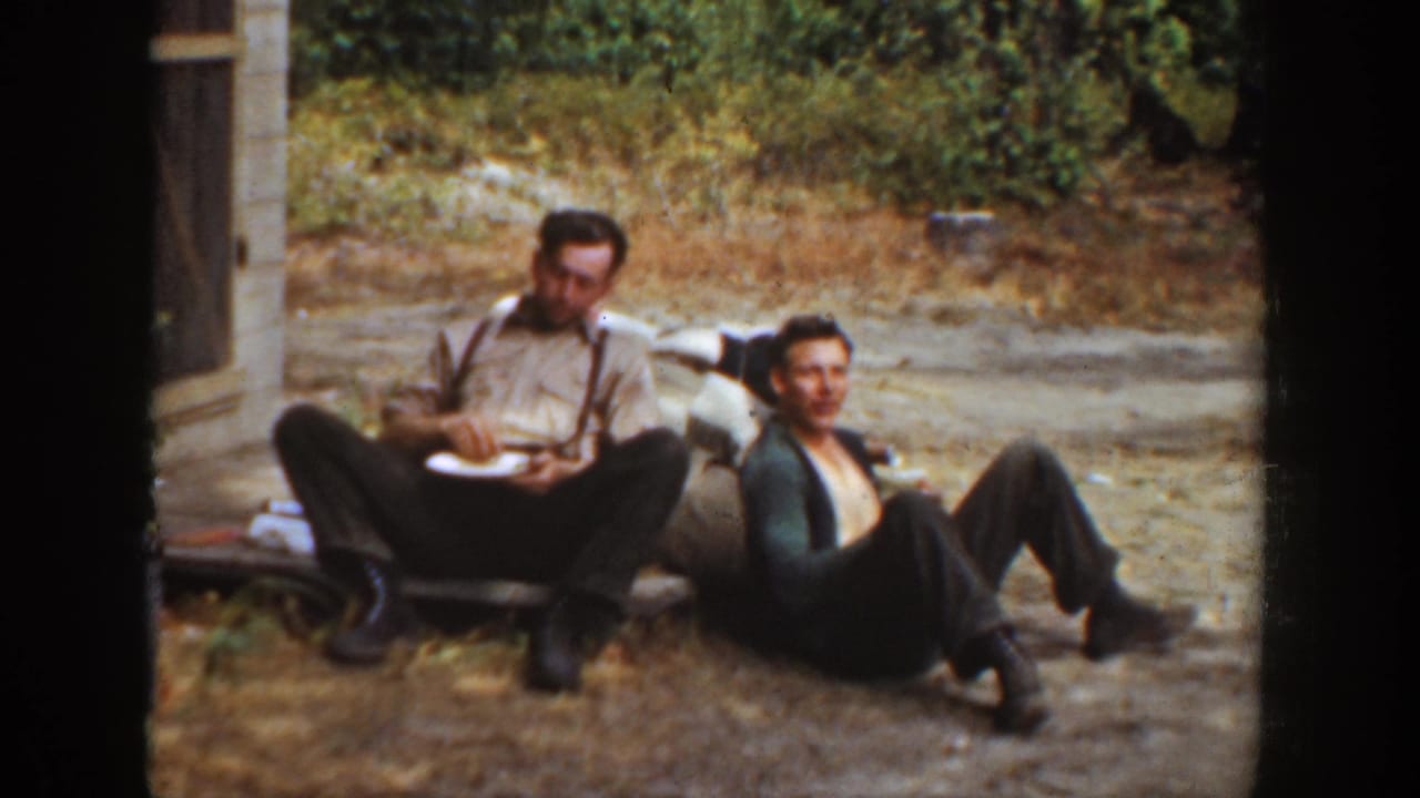 Two men remain seated outdoors, one holding a plate and the other reclining with knees raised.