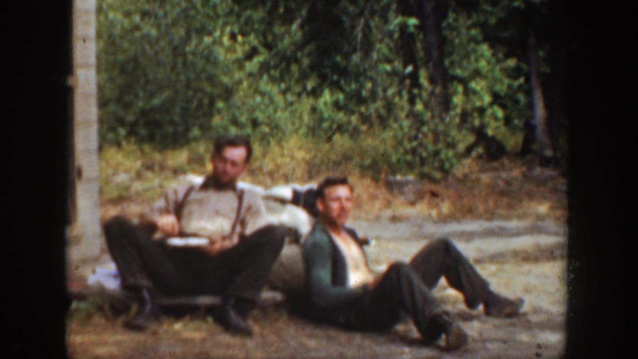 1936 California 8mm frame showing two adult men relaxing in a wooded outdoor area, with one man in suspenders eating from a plate.