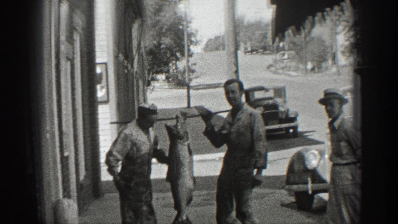 1936 California street scene with two men presenting a large hanging fish as another man stands nearby and vintage cars sit behind them.