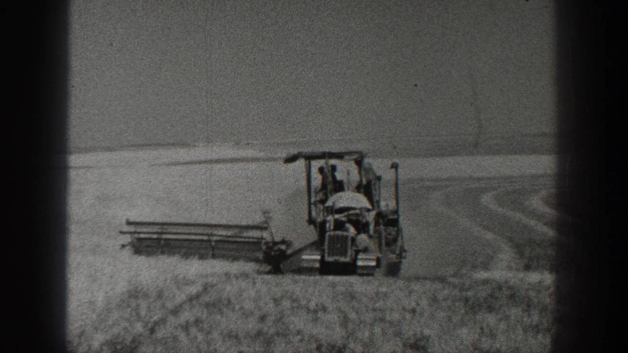 1936 California 8mm frame showing a farmer operating a tractor with a harvesting attachment in a field.