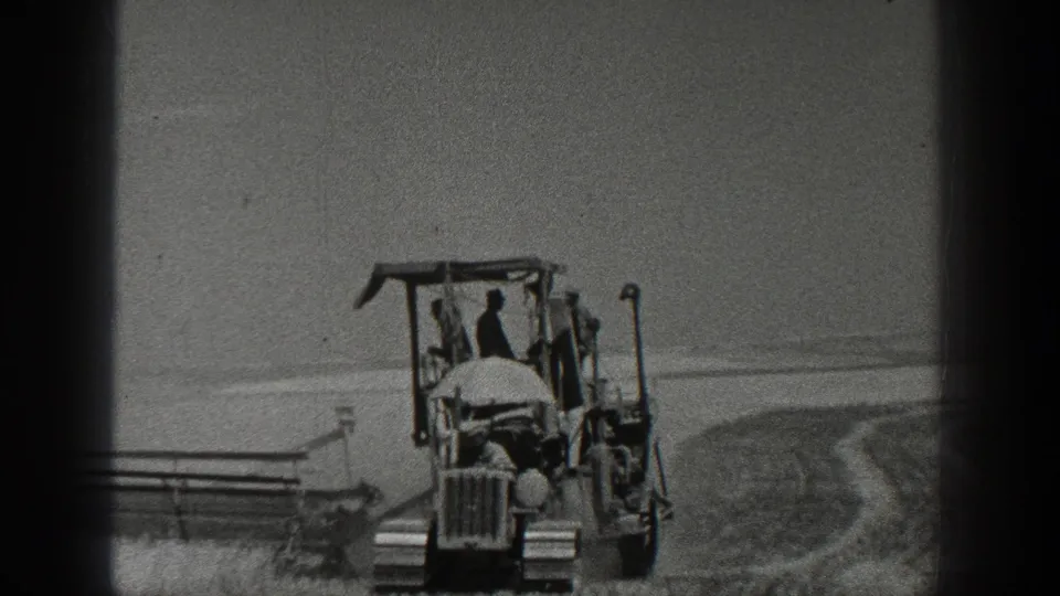 Closer 1936 California farm view with a tractor, visible operator, and attached harvester crossing the field.