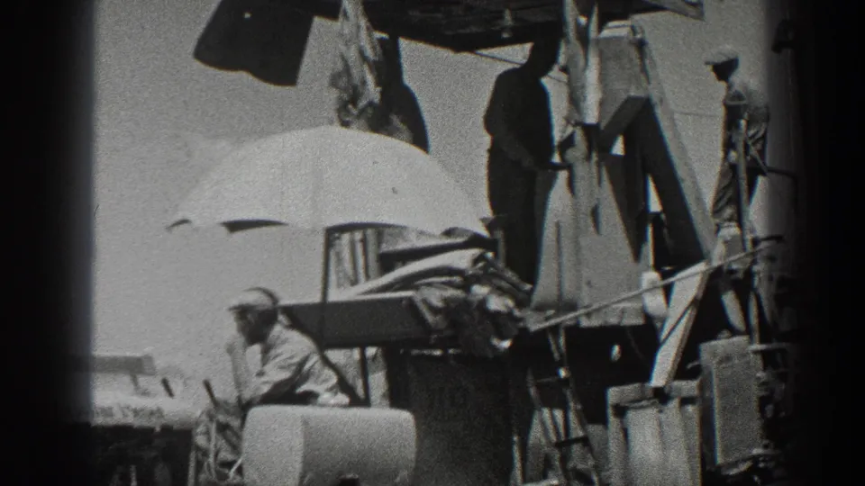1936 California 8mm frame showing rural workers around a combine harvester, with grain sacks and a shade umbrella on the machinery.