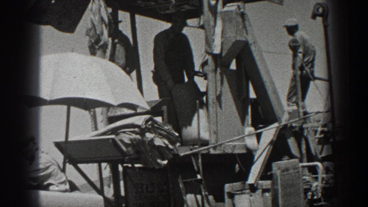 Men in work clothes operate or tend a 1936 California combine harvester, with a large umbrella shading part of the machinery.