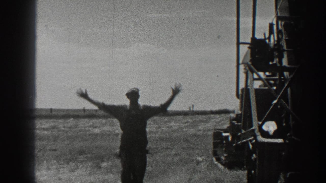 In 1936 California farm footage, a man in a cap stands near large field equipment and raises both arms against a flat horizon.