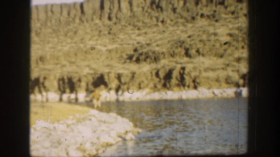 1936 California 8mm view of a broad river edge, pale rocky bank, and dry eroded terrain beyond.