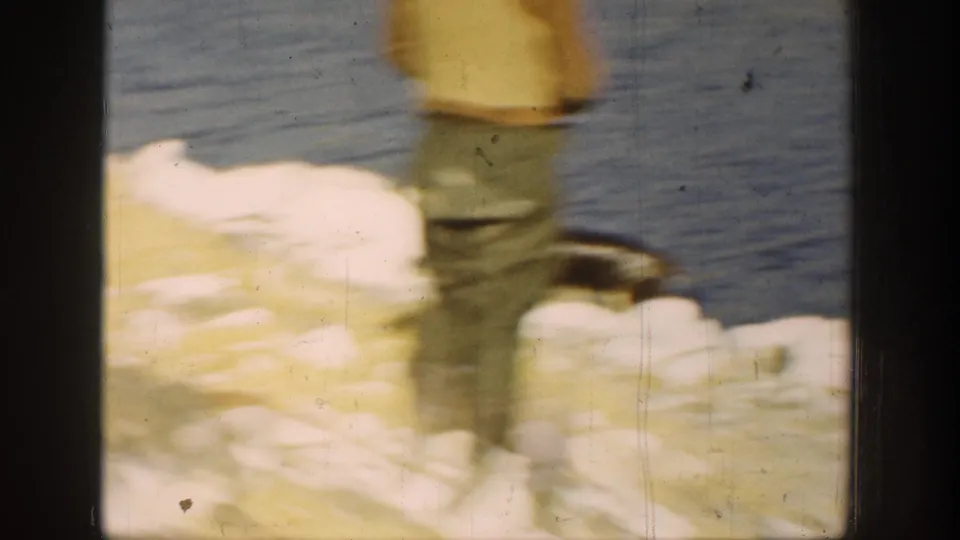 A person stands on a rocky California shoreline near the water in a soft, blurred 8mm home-movie frame from 1936.