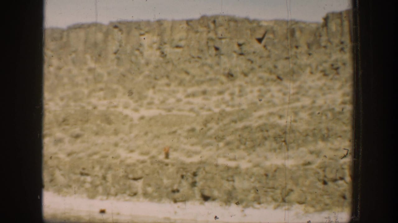 1936 California 8mm frame showing a dry hillside and calm water through dark window-like divisions.