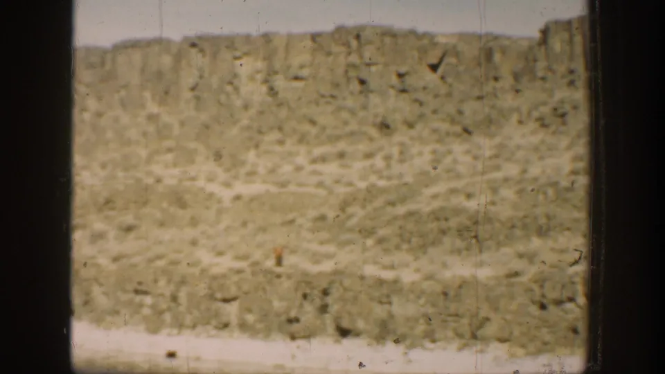 1936 California 8mm frame showing a dry hillside and calm water through dark window-like divisions.