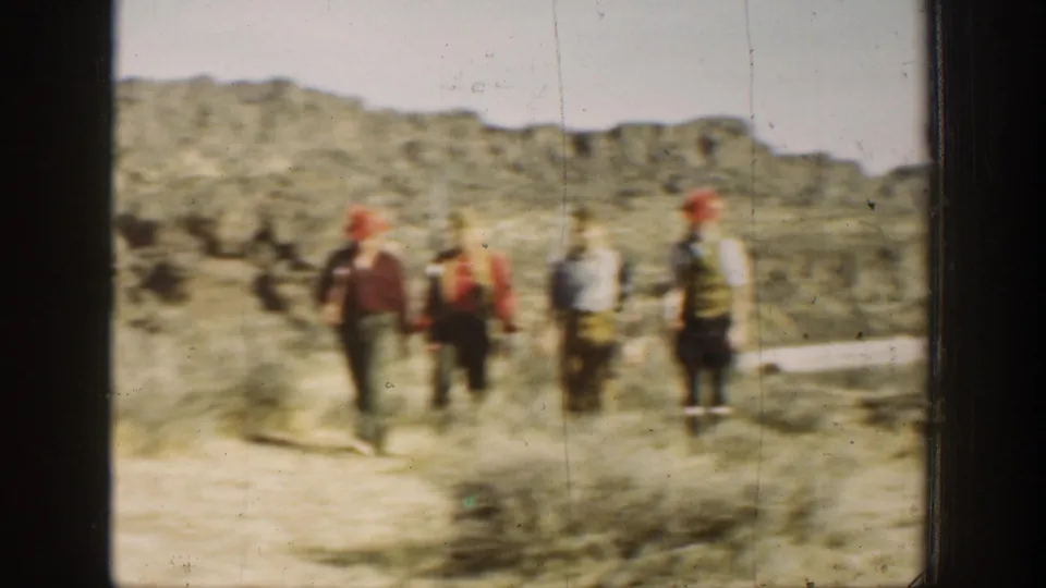 Four men carry long rifles while walking away across a dusty California landscape in a soft 1930s 8mm home-movie frame.
