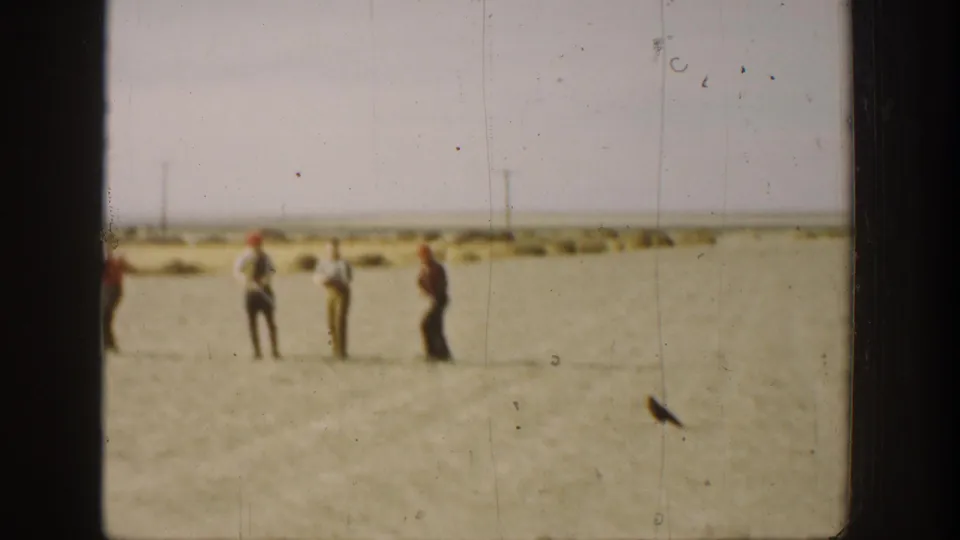 1936 California 8mm frame with distant men standing in an open field, possibly preparing for or observing a hunt.