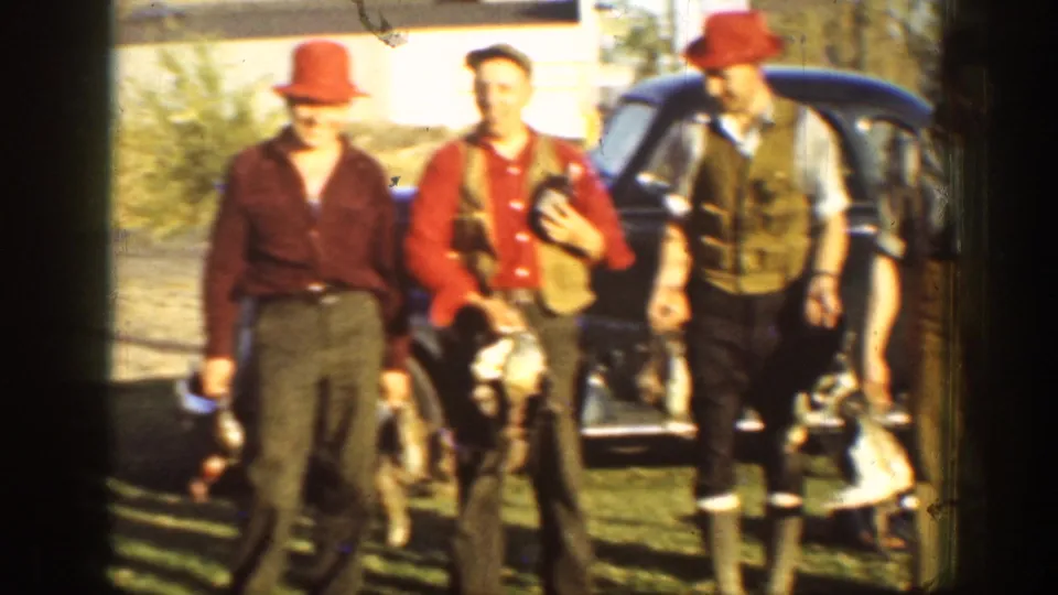 In 1936 California home-movie footage, three adult hunters pose near a dark car with game birds and period outdoor clothing.