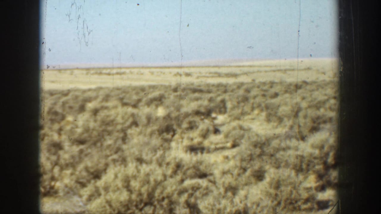 1936 California 8mm view of dry scrubland and a low horizon seen through dark window-like frame edges.