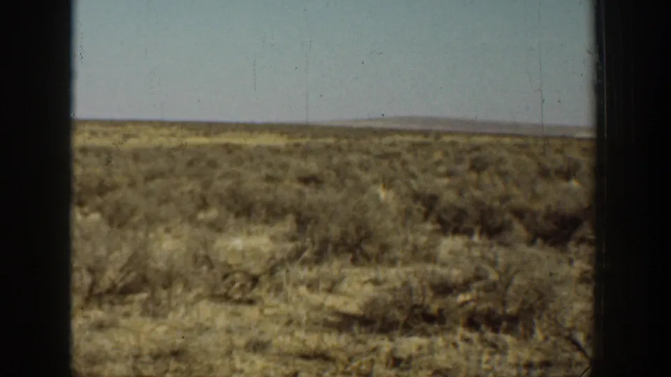 1936 California 8mm frame of dry grassland and scrub with distant hills and visible film wear.